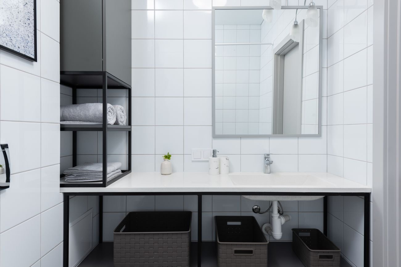 Neatly folded towels on open shelving in a spotless, bright bathroom