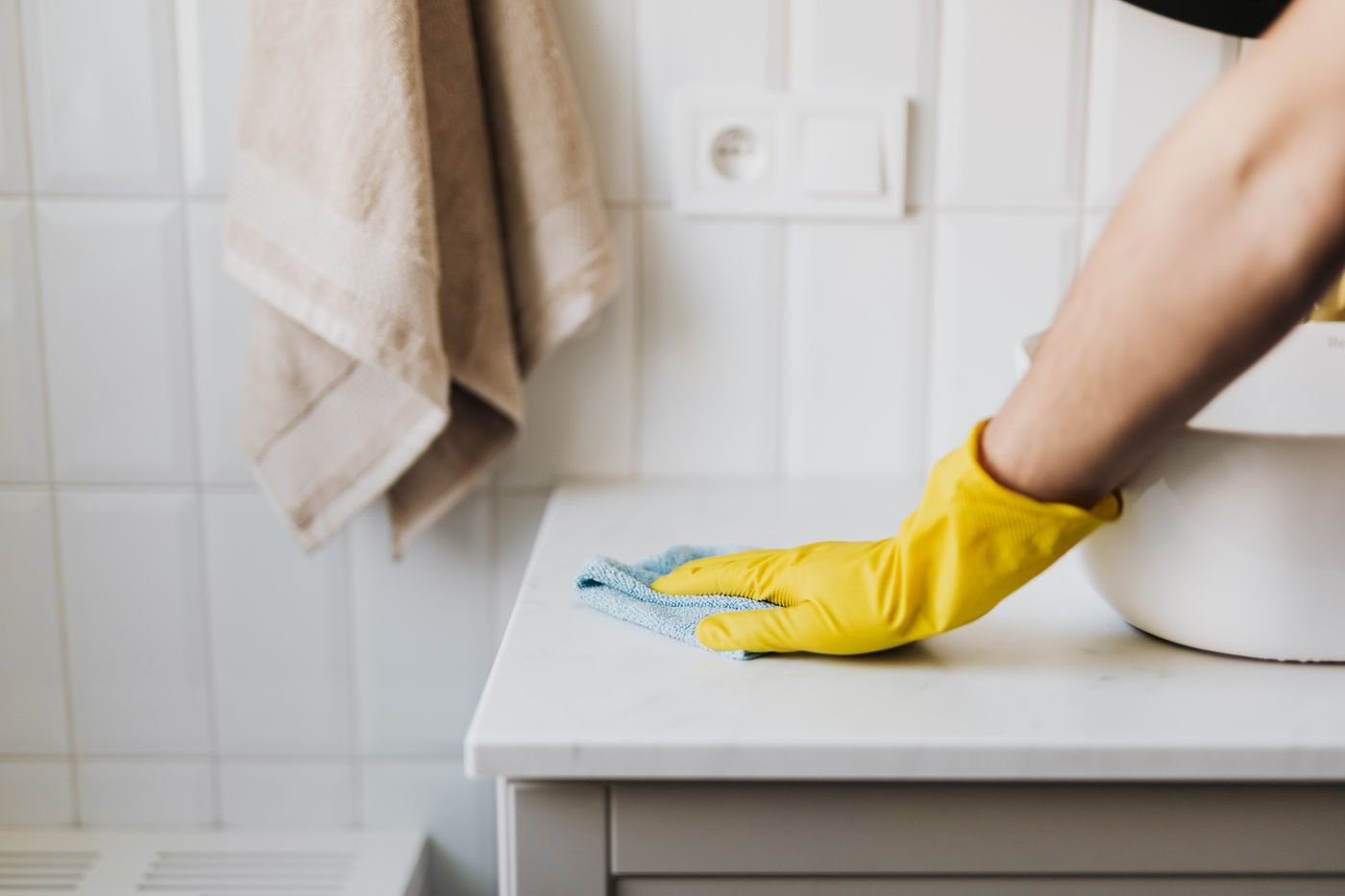 A cleaner's gloved hand wiping a counter until it shines